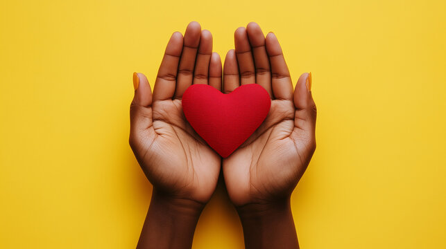 indian woman's hands holding red heart in her open palms. isolated on yellow background