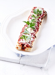 Open-faced toasted salami and cheese sandwich on bright background.