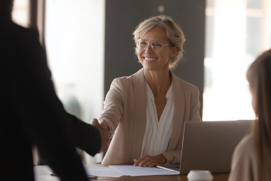 Smiling businesswoman shaking hands with a client.  Successful meeting, positive business.