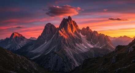 Mountain range at sunset with colorful sky and cloud above the peak.