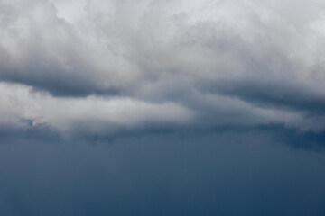 Obraz premium Thick storm clouds stretch across the sky with a visible curtain of rain falling below, creating a dramatic and moody atmosphere ample copy space.