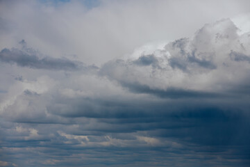 Dark, dense storm clouds gather across the sky, with heavy rain visible in the distance and a few lighter clouds at the bottom ample copy space.