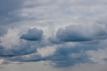Fototapeta premium Dark, dense storm clouds gather across the sky, with heavy rain visible in the distance and a few lighter clouds at the bottom ample copy space.