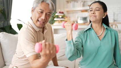 Happy elderly couple exercising together with dumbbells at home, focusing on muscle strength, joint health, and physical wellness for improved mobility and healthy aging. Retirement concept. Myrmidon.