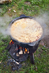 Top view of the cooking process of pilaf over an open fire in a cauldron on a grill, with boiling...