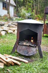 Front view of a cauldron stand with a kazan used for cooking Tajik pilaf outdoors on the grass...