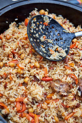 Top view of ready-made oriental pilaf in a black cauldron placed on an outdoor table