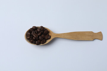 Hot coffee in a white coffee cup and many coffee beans scattered around 