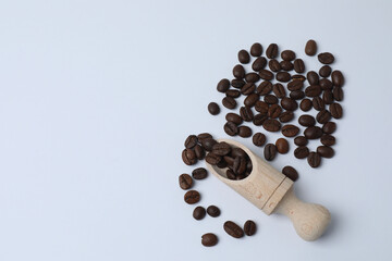 Hot coffee in a white coffee cup and many coffee beans scattered around 