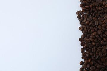 Hot coffee in a white coffee cup and many coffee beans scattered around 