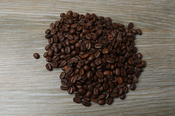 Hot coffee in a white coffee cup and many coffee beans scattered around 