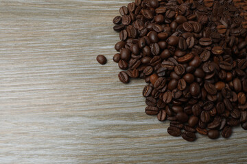 Hot coffee in a white coffee cup and many coffee beans scattered around 