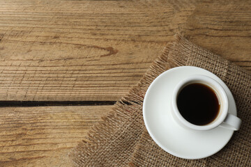 Hot coffee in a white coffee cup and many coffee beans scattered around 