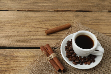 Hot coffee in a white coffee cup and many coffee beans scattered around 
