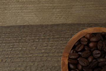 Hot coffee in a white coffee cup and many coffee beans scattered around 