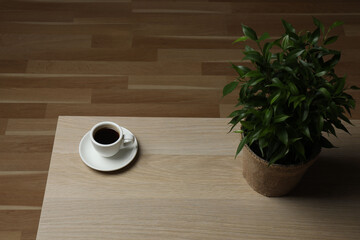 Hot coffee in a white coffee cup and many coffee beans scattered around 