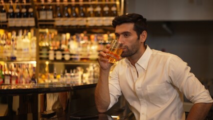 Smart man in white shirt drinking cocktail Old fashioned waiting friends or couple while chatting on smartphone in special party beverage vibrant at nightclub on Friday meeting night time. Vinosity.