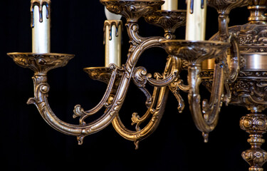 Part of a bronze chandelier with light bulbs on a black background