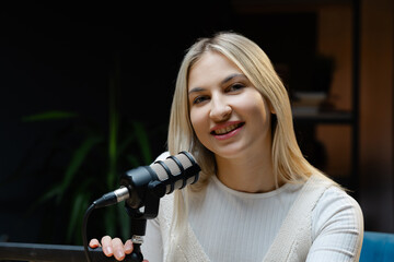 Smiling woman speaking into a microphone recording a podcast