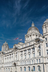 White Building with Domes and Flags Against Blue Sky in Liverpool, UK.