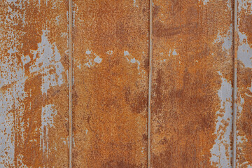 Close-up of an old rusted metal wall with vertical lines and textured surface. Corroded industrial steel background with orange and brown oxidation pattern. Ideal for grunge, vintage, or construction.