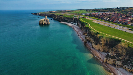 Aerial View of Cliffside Coastline with Rock Formation, Beach, and Coastal Town at Marsden Beach, UK
