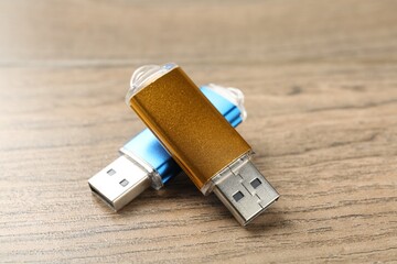 Two flash drives on wooden background, closeup