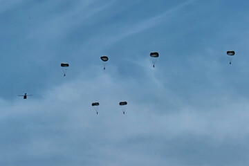 Army Paratroopers leap from a helicopter during a military training exercise, showcasing airborne deployment skills