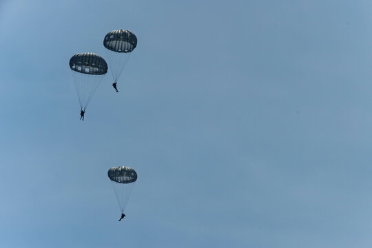 Army Paratroopers leap from a helicopter during a military training exercise, showcasing airborne deployment skills