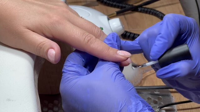 Gel varnish coating. close-up. video. The manicure coats nails with gel polish in the beauty salon.