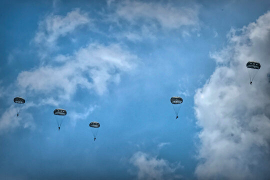 Army Paratroopers leap from a helicopter during a military training exercise, showcasing airborne deployment skills
