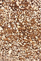 Compact gravel stones covering dry brown soil
