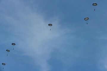 Army Paratroopers leap from a helicopter during a military training exercise, showcasing airborne deployment skills