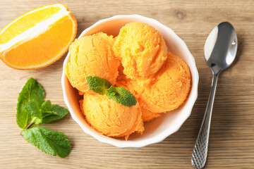 Tasty orange sorbet, fresh fruit slice and mint on wooden table, flat lay
