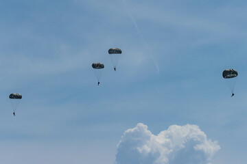 Army Paratroopers leap from a helicopter during a military training exercise, showcasing airborne deployment skills