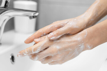 Woman washing hands at sink in bathroom, closeup