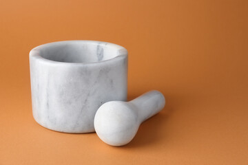 Marble mortar and pestle on light brown background, closeup. Space for text