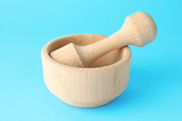 Wooden mortar and pestle on light blue background, closeup