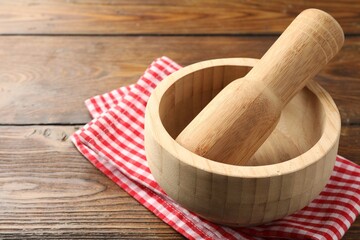 Mortar, pestle and cloth on wooden table, closeup