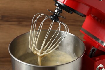 Stand mixer with dough on wooden table, closeup