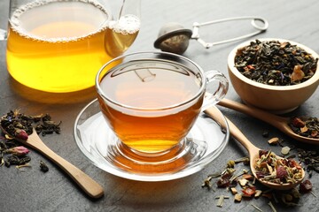 Delicious herbal tea and dry leaves on black table, closeup