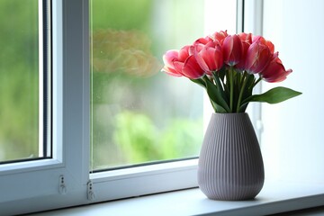 Beautiful tulips in vase on window sill. Space for text