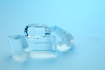 Cubes of clear ice on light blue background, closeup