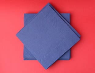 Stack of blue handkerchiefs on red background, top view