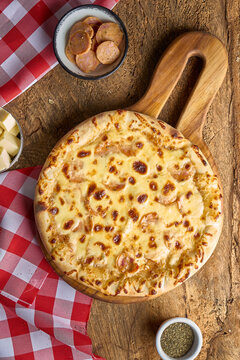 pizza de chorizo con queso en fondo de madera y mantel rojo de cuadros
