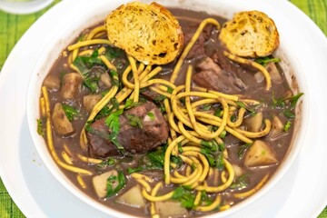 Traditional black bean soup with noodles and pork ribs, rustic Brazilian food known as sopa preta or sopa de benzedeira