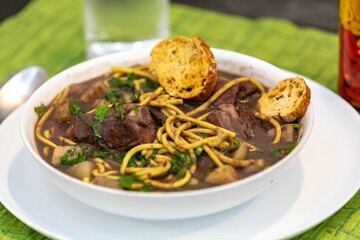 Traditional black bean soup with noodles and pork ribs, rustic Brazilian food known as sopa preta or sopa de benzedeira