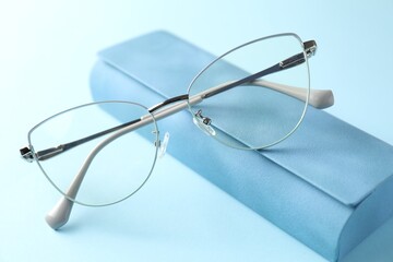Case with stylish glasses on light blue background, closeup