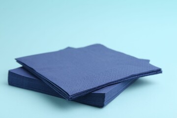 Stack of disposable paper handkerchiefs on light blue background, closeup