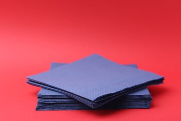 Stack of blue handkerchiefs on red background, closeup. Space for text